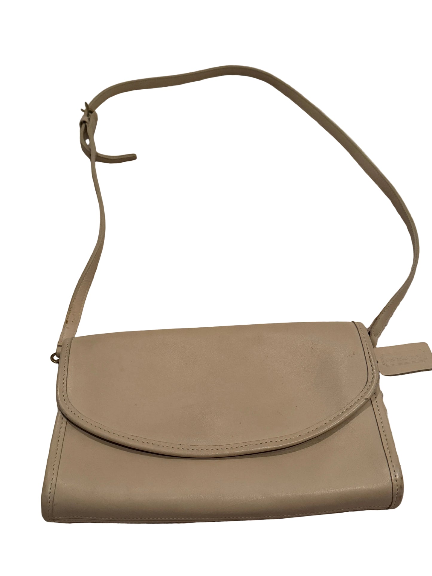 A beige leather crossbody bag with a long strap, laid flat on a textured light beige carpet.
