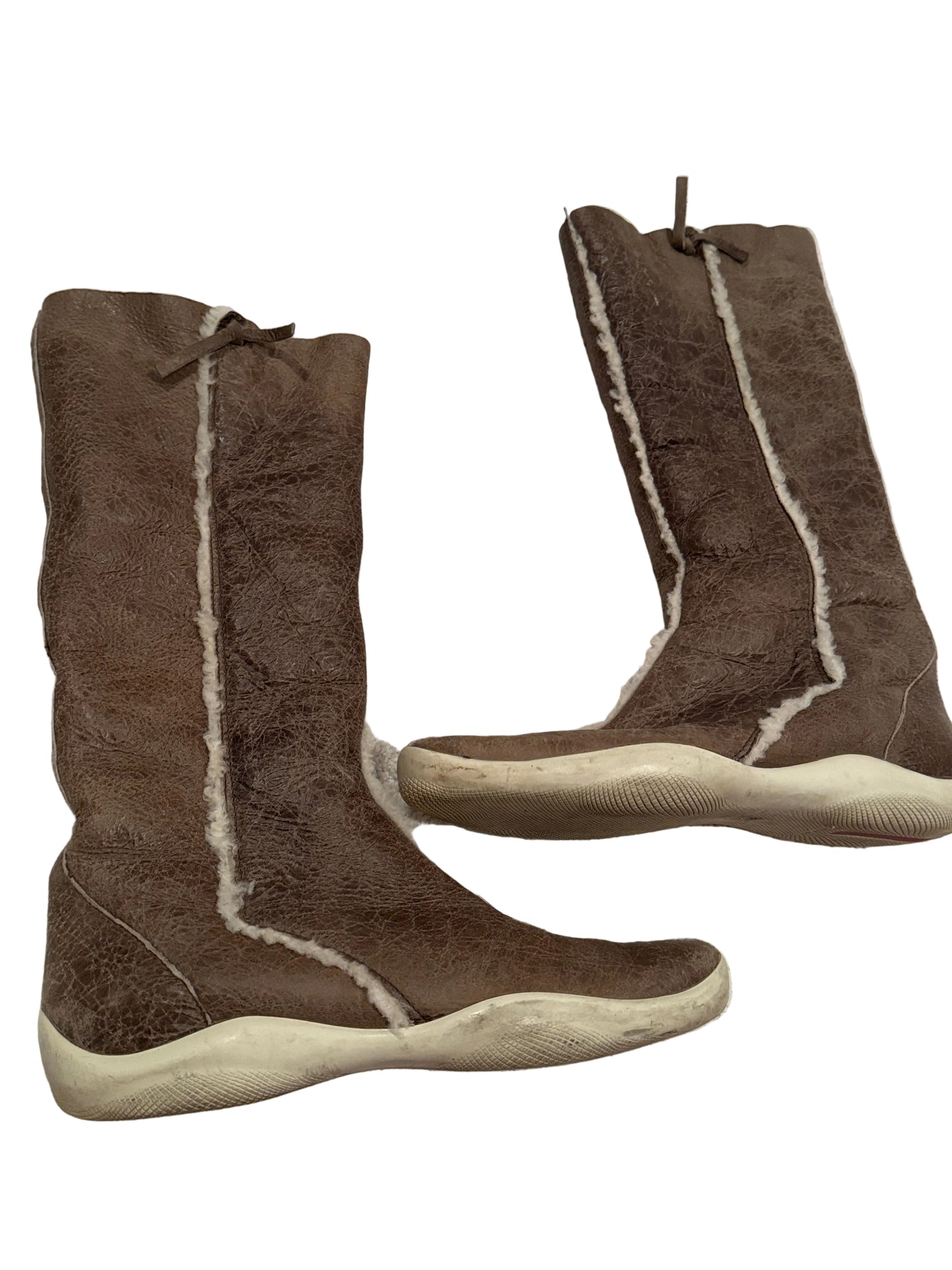A pair of brown suede-like boots with cream shearling-style lining and thick cream-colored soles, photographed on a light beige carpet.